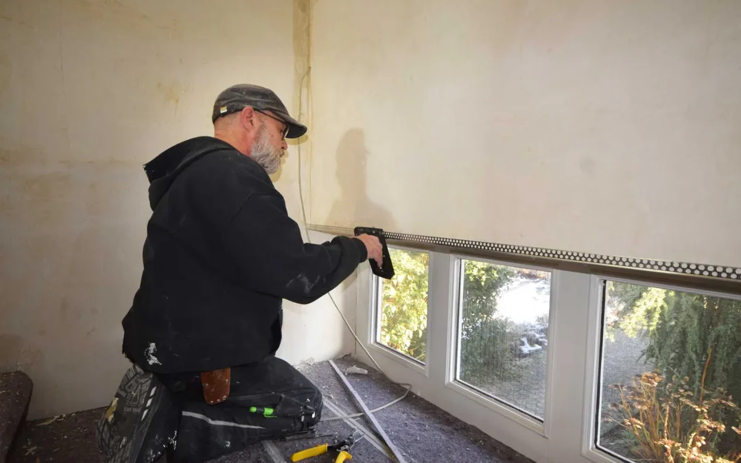 Mitarbeiter bei der Montage eines Profils an der Wand unter den Fenstern