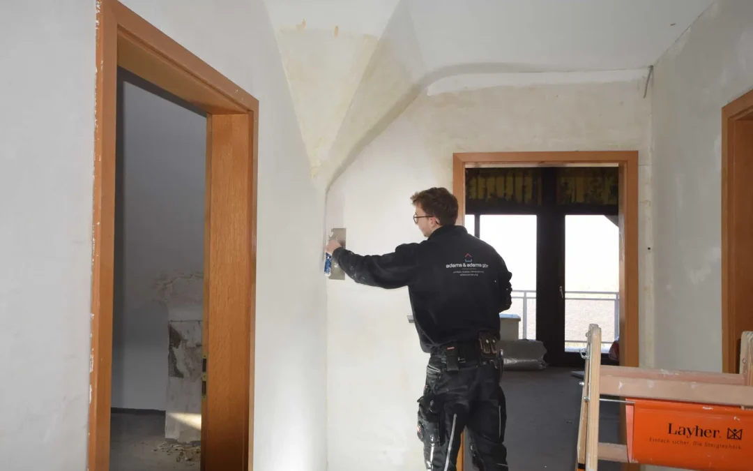 Mitarbeiter beim Spachteln einer Wand neben einer Tür