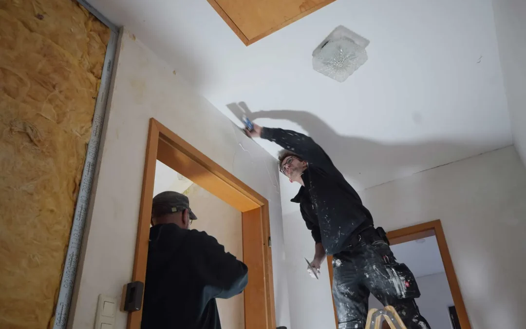 Mitarbeiter bei Deckenarbeiten auf einer Leiter neben einer Trockenbauwand